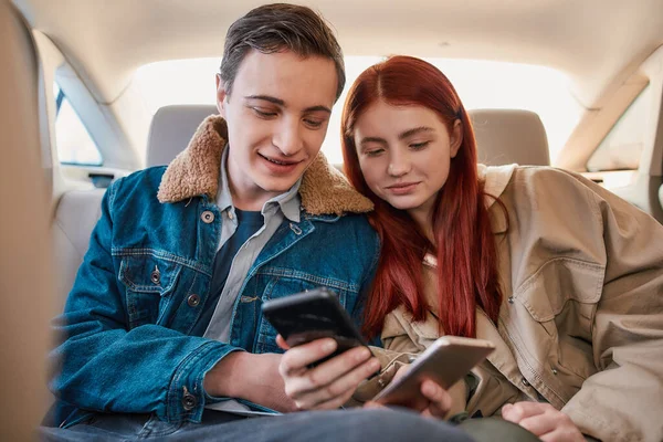 Μερικοί έφηβοι χρησιμοποιούν τα smartphones τους ενώ κάθονται στο πίσω κάθισμα του αυτοκινήτου — Φωτογραφία Αρχείου