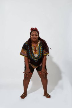 Artı geniş bacaklı ve dizlerinin üzerinde elleri olan bir kadın.