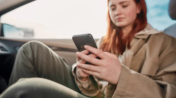Πορτρέτο του έφηβος κορίτσι κοιτάζοντας την οθόνη, ενώ χρησιμοποιώντας το τηλέφωνό της, κάθεται στο αυτοκίνητο. Έννοια εξάρτησης από smartphone — Φωτογραφία Αρχείου
