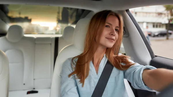 Portret van een jonge blanke vrouw in een moderne auto — Stockfoto