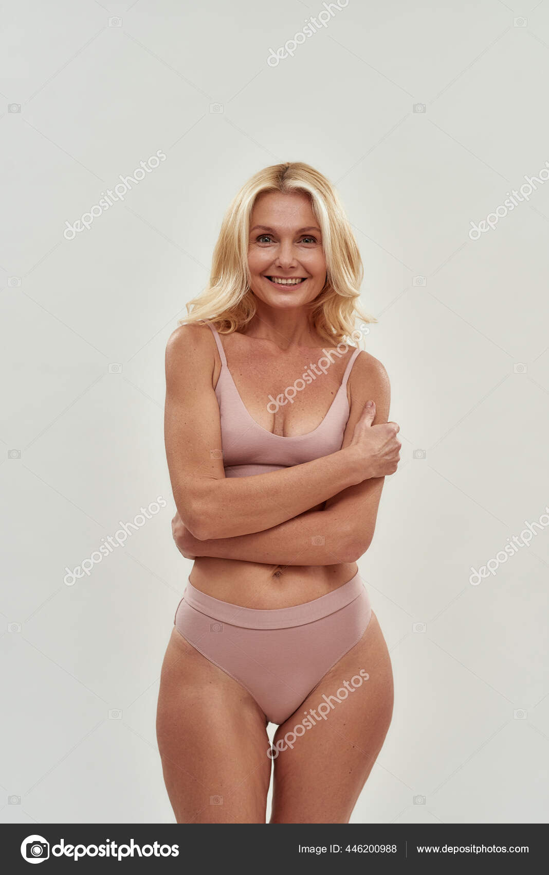 Beautiful blonde girl in light pink lingerie posing on a white background.  Advertising Space Stock Photo