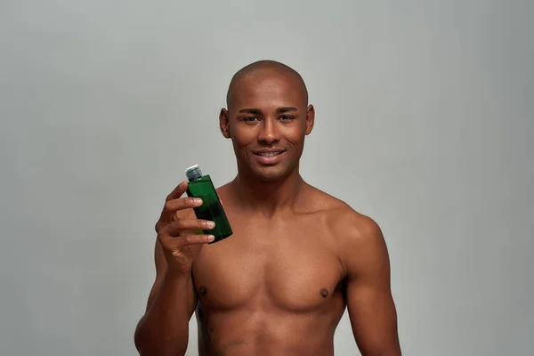 İddialı erkek, yeşil bir şişede losyon saklıyor. — Stok fotoğraf