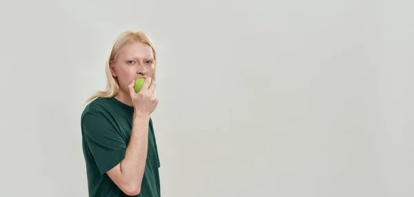 快乐的年轻高加索人吃着青葱多汁的苹果 — 图库照片