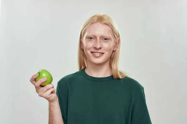 Sonriente joven caucásico hombre sosteniendo verde jugosa manzana — Foto de Stock