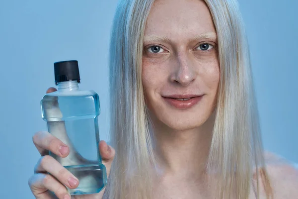 Smiling young caucasian man holding mouthwash liquid — Stock Photo, Image