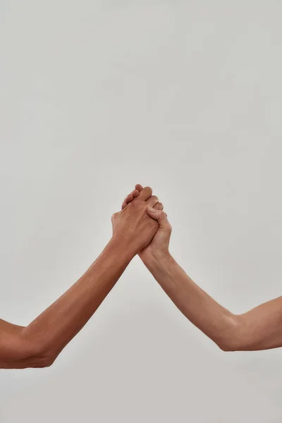 Close up of two hands holding each other, gesture of support isolated over light background — стоковое фото