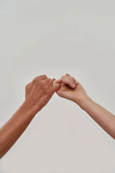 Közelkép két kéz horog kisujj együtt ígérni, vagy kéri a megbékélés elszigetelt fény háttér — Stock Fotó