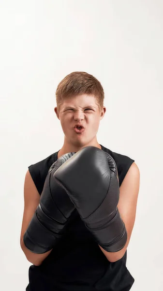 Porträt eines fröhlichen behinderten Jungen mit Down-Syndrom, der große Boxhandschuhe trägt und emotional wirkt, während er isoliert vor weißem Hintergrund posiert — Stockfoto