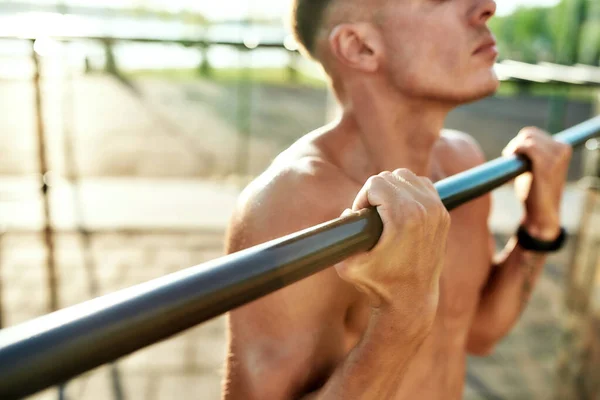 Young athlete on horizontal bar during workout on sport ground — Stock Photo, Image