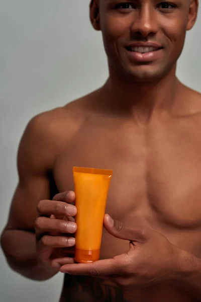Oranje tube aangeboden door een Afro-Amerikaanse volwassene — Stockfoto
