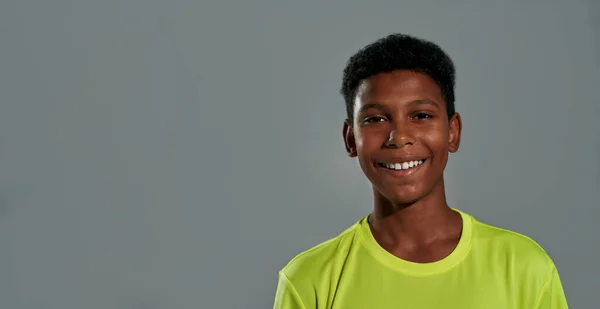 Портрет веселого підлітка африканського хлопчика, який посміхається на камеру, позує ізольовано на сірому фоні — стокове фото