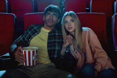 Odaklanmış genç bir çift, çekici erkek ve kadın sinemada oturuyor, coşkuyla film izliyor ve el ele tutuşuyorlar.