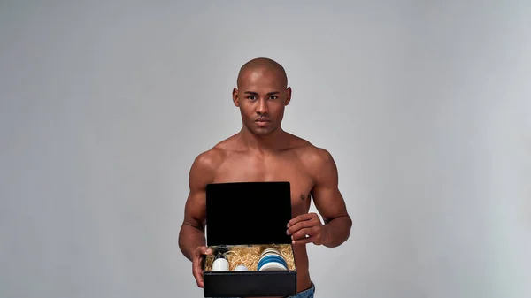 Muscular masculino segurando uma caixa com vários cremes — Fotografia de Stock