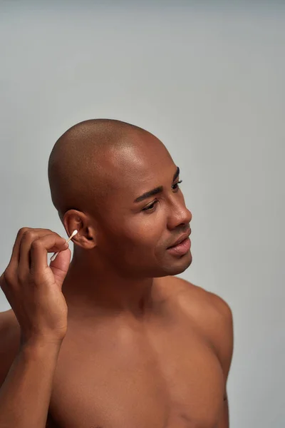 Homem cauteloso conectando um botão de algodão em seu ouvido — Fotografia de Stock