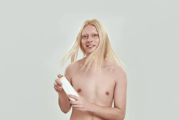 Модель струшування голови з світлим волоссям, тримаючи шампунь — стокове фото