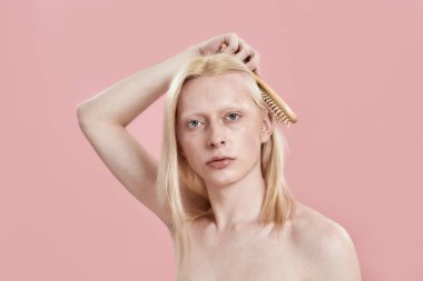 Kafkasyalı genç uzun saçlarını kafasının üstünde tarıyor.