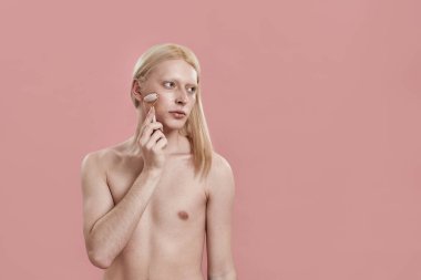 Genç beyaz adam yanak masajı için kuvars silindiri kullanıyor.