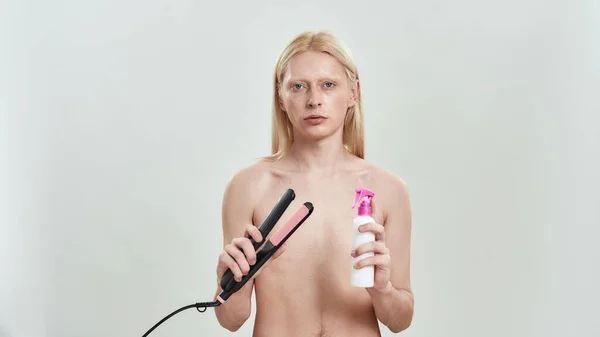 Young caucasian man holding tools for hair straightening — Stock Photo, Image