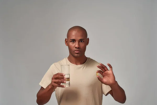 Masculino com uma pílula e um copo de água — Fotografia de Stock