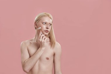 Genç beyaz adam yüz masajı için kuvars silindiri kullanıyor.