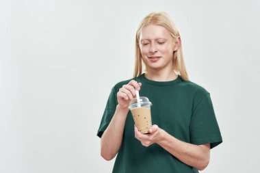 Kafkasyalı mutlu genç bir adam kahvesini fincanda karıştırıyor