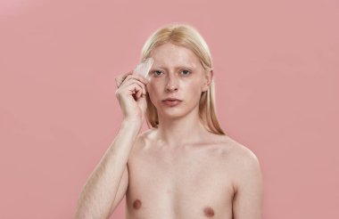 Kafkasyalı genç adam alnında kuvars masajcısı kullanıyor.