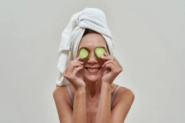 Middle aged woman with cucumber slices on eyes — Stock Photo, Image