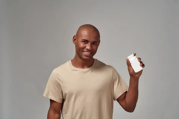 Weergave van een pil fles in een vreugdevolle man arm — Stockfoto
