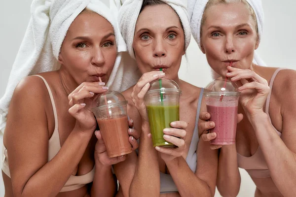 Portrait of middle aged women drinking smoothies through straws — Stock Photo, Image