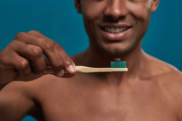 Lachende persoon die een tandenborstel vasthoudt met een donkere tablet — Stockfoto