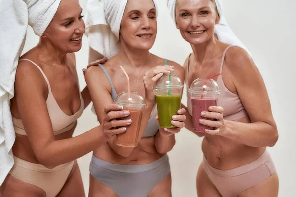 Happy middle aged women clinking cups with smoothies — Stok Foto