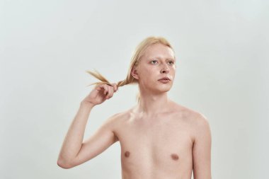 Kafkasyalı genç adam uzun sarı saçlarını elinde tutuyor.