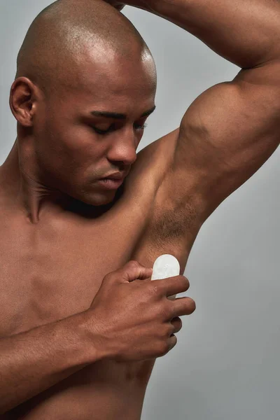 Athletic male running a crystal deodorant stone over armpit skin — Stock Photo, Image