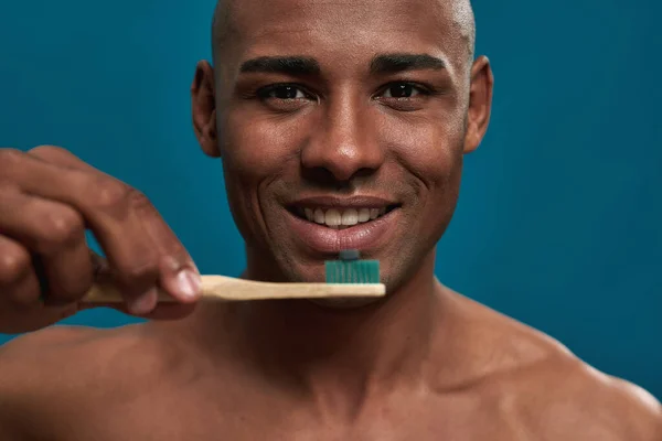 Blij man brengt een tandpasta capsule op een tandenborstel — Stockfoto