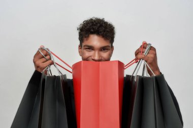 Elinde açık bir alışveriş çantası tutan neşeli genç çocuk.