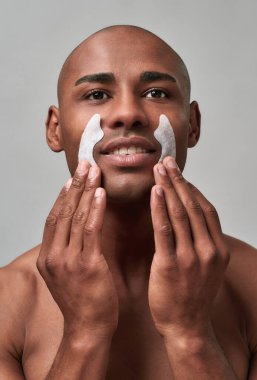 Yüzü gülen kişi cildine kırışık bantlar yapıştırıyor.