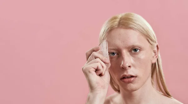 Young caucasian man using quartz tool for face massage — Stock Photo, Image