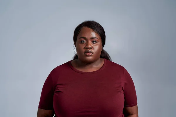 Retrato de grave plus size jovem afro-americana em roupas casuais de pé isolado sobre fundo cinza — Fotografia de Stock