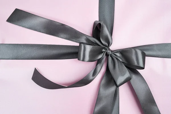 Holidays and celebration concept. Top view of a pink wrapped gift box with grey bow, close up shot