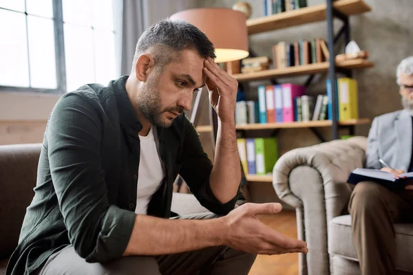 Depressieve jonge Kaukasische man tijdens een afspraak met psychotherapeut — Stockfoto