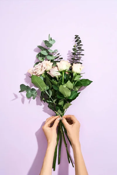 Best gift for your woman. Top view of a female florist making beautiful bouquet for 8 March and International Womens day on purple background