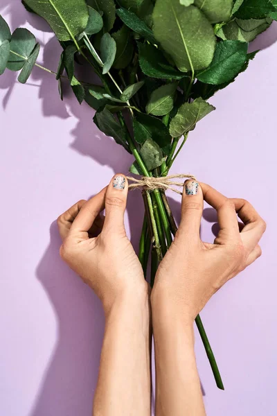 Bovenaanzicht van een vrouwelijke bloemist maken mooi boeket voor 8 Maart en International Womens dag op paarse achtergrond — Stockfoto