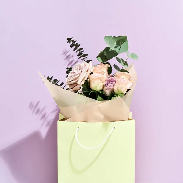 Fijne Moederdag. Mooie en verse bloemen boeket in papieren geschenkzak over paarse achtergrond — Stockfoto