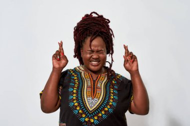 Gözleri kapalı tombul kadın parmaklarını çapraz tutuyor.