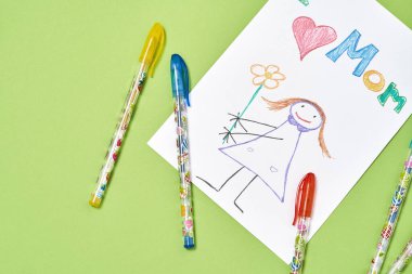 Seni seviyorum, anne. Yeşil arka planda, anneler günü için renkli kalemlerle renkli çocuk çizimlerinin üst görüntüsü