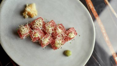 Beyaz tabakta wasabi ve zencefil ile servis edilen lahanalarla süslenmiş lezzetli suşi rulosu seti. Sağlıklı gurme çiğ yemek.