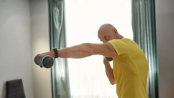 Adult trainer exercising at home with dumbbells