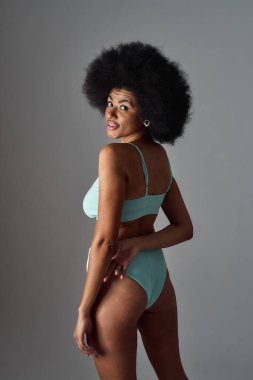 Baştan çıkarıcı, saç stili, mavi iç çamaşırı giyen, gri arka planda yalnız poz veren, baştan çıkarıcı, genç bir ırk kadını.