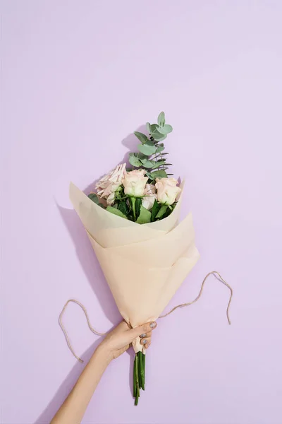 Gesneden schot van vrouwelijke bloemist met verse bloemen boeket over paarse achtergrond, bovenaanzicht — Stockfoto