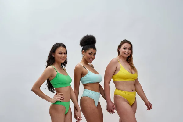 Full length shot of three proud diverse women with different body shapes in colorful  underwear walking towards camera together isolated over light background  Stock Photo by ©LanaStock 454647210